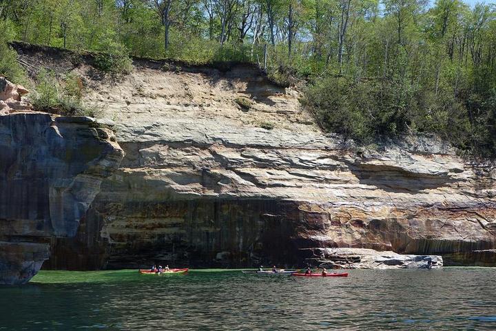 Kayakers paddling along the Pictured Rocks cliffs