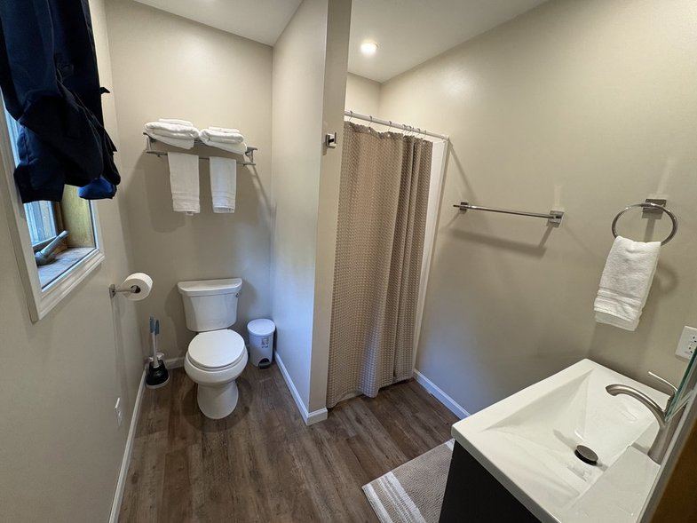 Bright bathroom with towels, toilet, shower and vanity